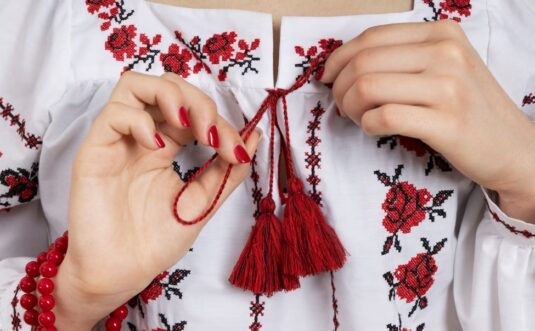 a woman with raid nails wearing a beautiful embroidered shirt