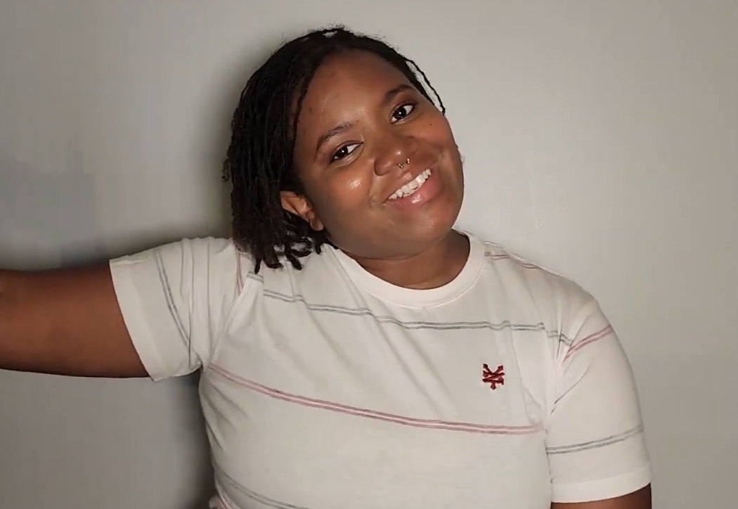 woman in white t-shirt standing in front of wall and smiling