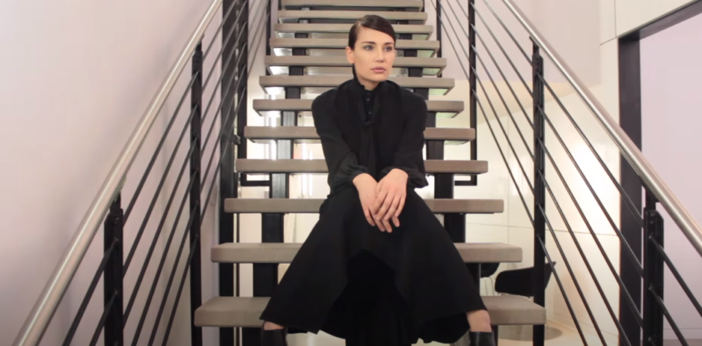 A woman dressed in all black, seated on the stairs