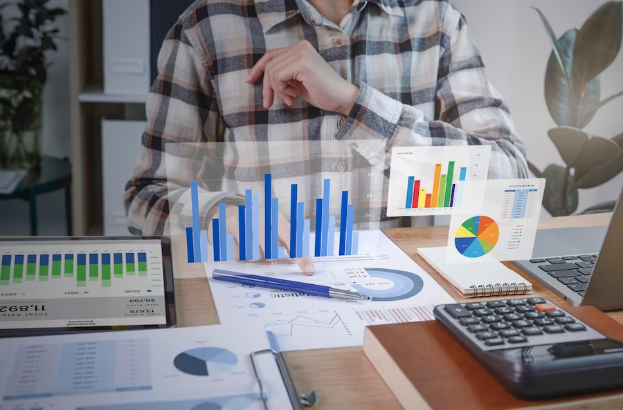 Person working at a table with financial data and graphics overlay related to data and finance