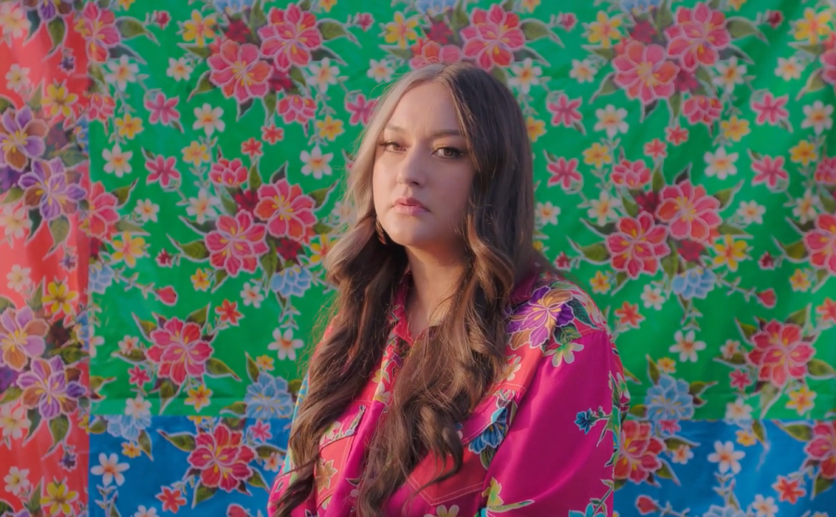 Brenda Equihua standing in front of colorful cloth with flowers on it